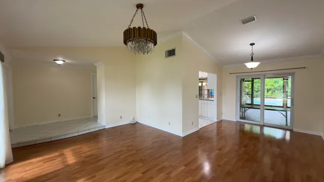 an empty room with wooden floor a ceiling fan and windows