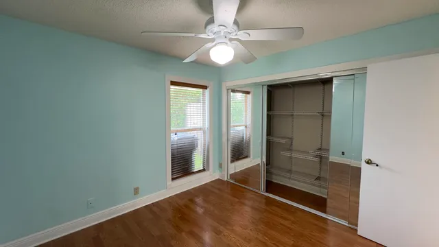 an empty room with closet and a chandelier fan