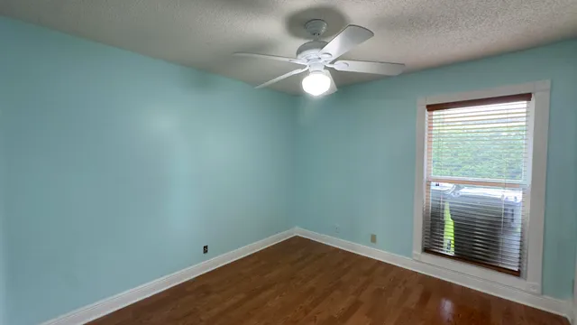 an empty room with a window and ceiling fan