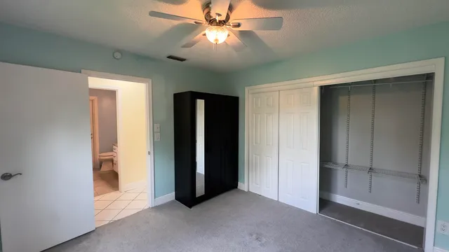an empty room with closet and a chandelier fan
