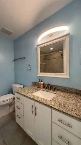 a bathroom with a granite countertop toilet sink and mirror