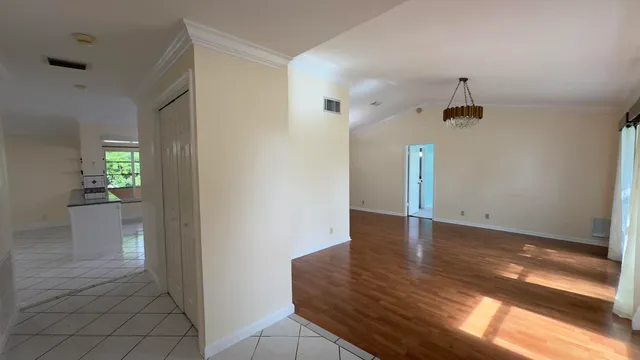 a view of an empty room with window and wooden floor