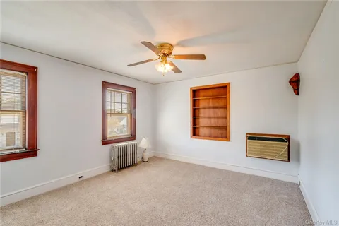 a view of an empty room with a window and a ceiling fan