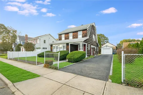 a front view of a house with a yard and potted plants