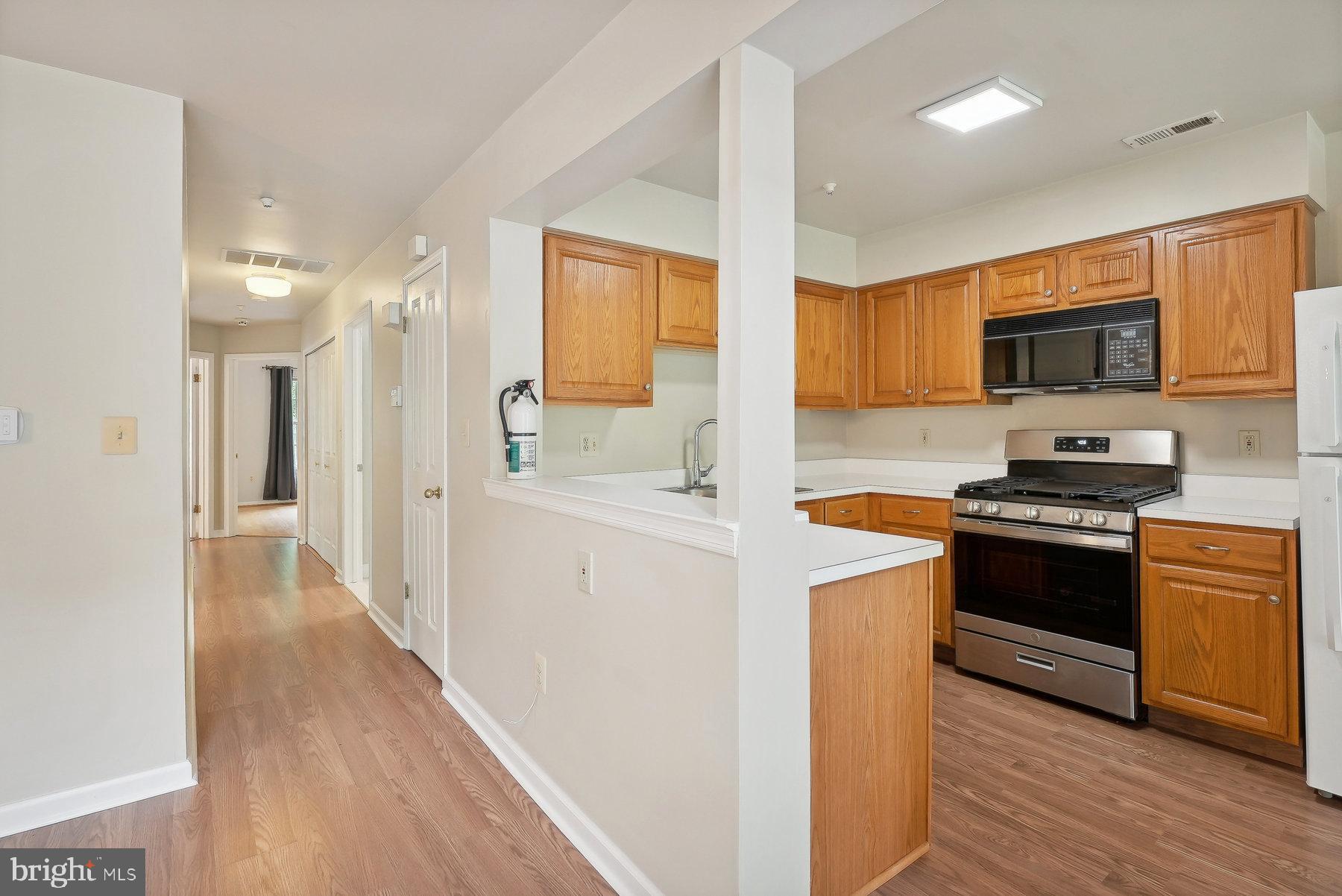 624 Brickhouse Road Princeton, NJ 08540 - Photo 12 of 35 a kitchen with stainless steel appliances a stove top oven a sink a refrigerator white cabinets and wooden floor