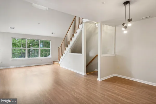 a view of a livingroom with wooden floor staircase and a kitchen space