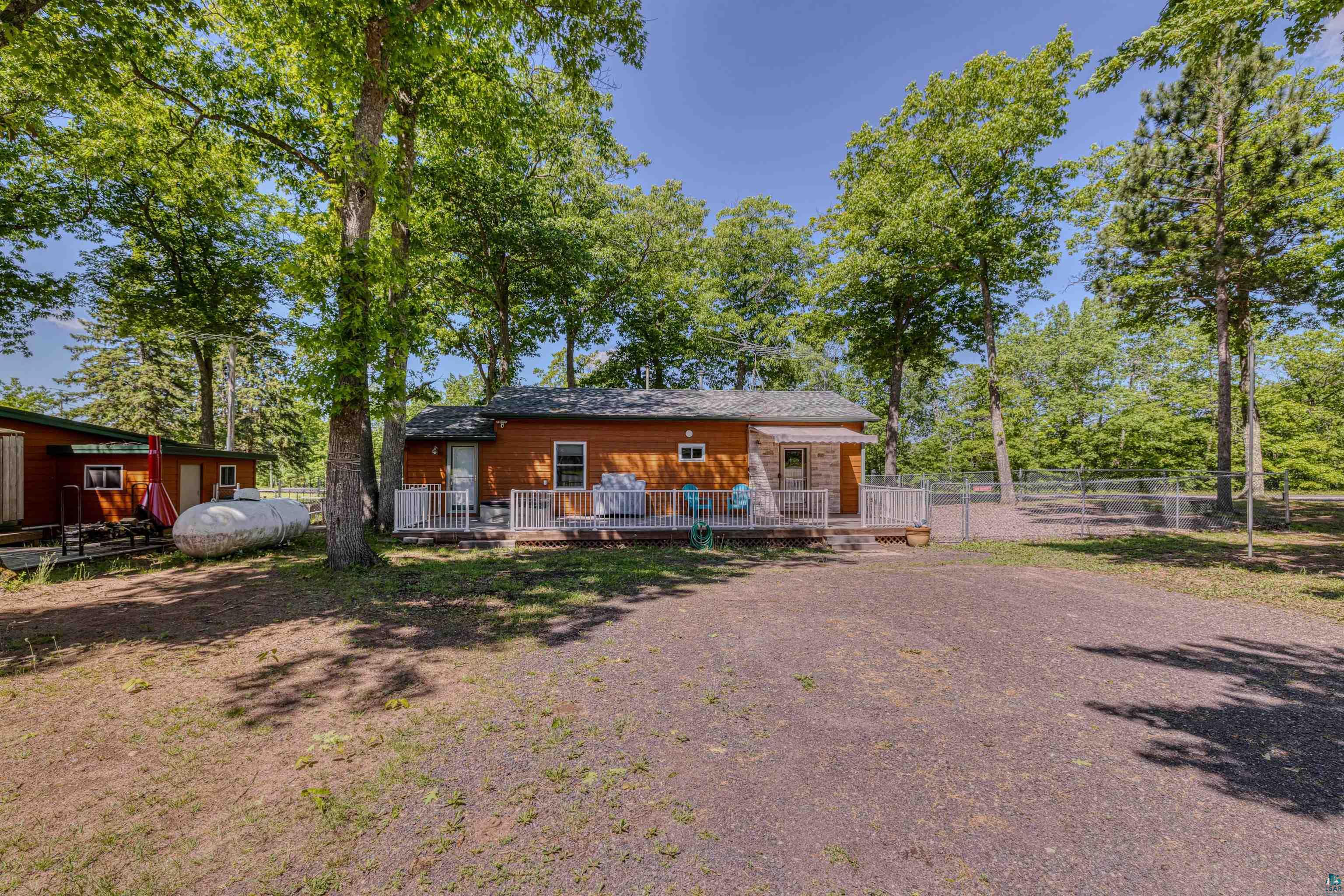 66075 Rooster Road Iron River, WI 54847 - Photo 37 of 52 Wood-sided dwelling with a white railing deck and gravel parking area