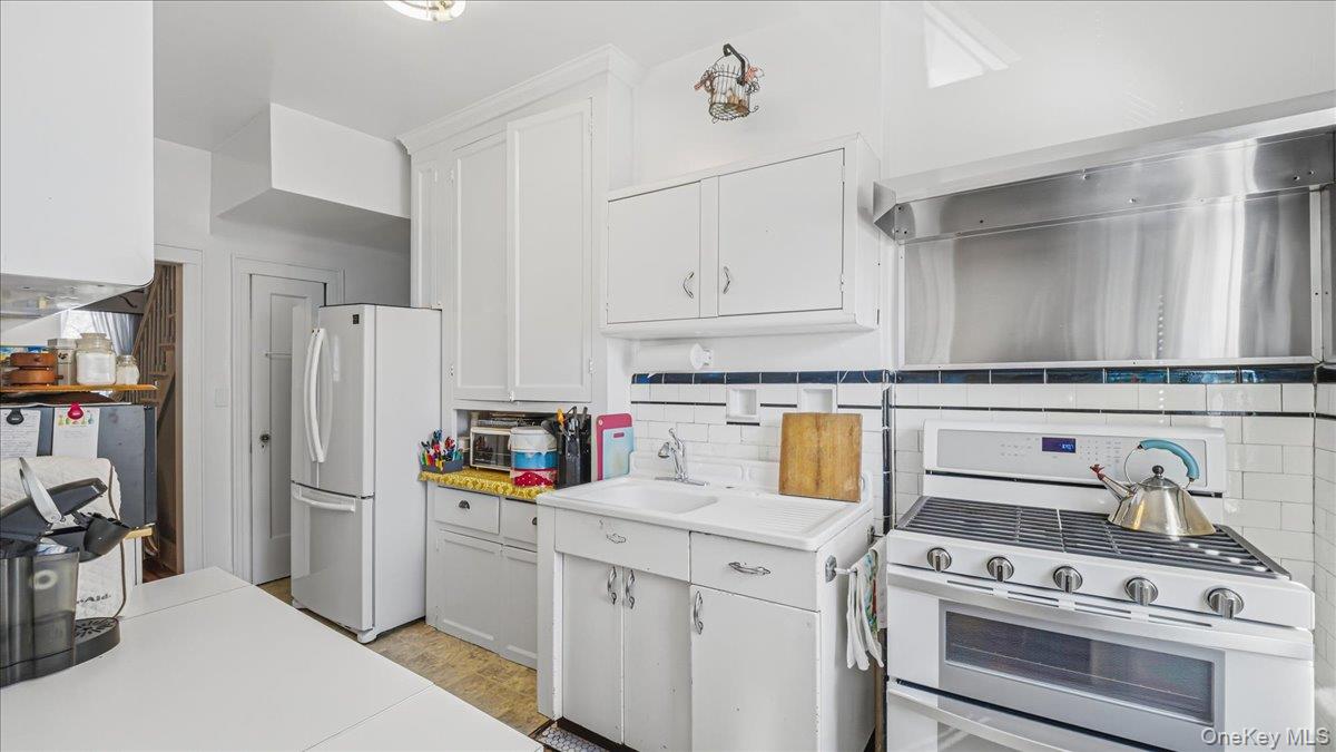 52-61 66th Street Queens, NY 11378 - Photo 6 of 26 a kitchen with white cabinets and white appliances