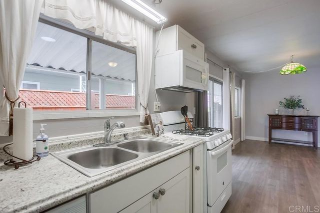 a kitchen with stainless steel appliances granite countertop a sink a stove and a wooden floors