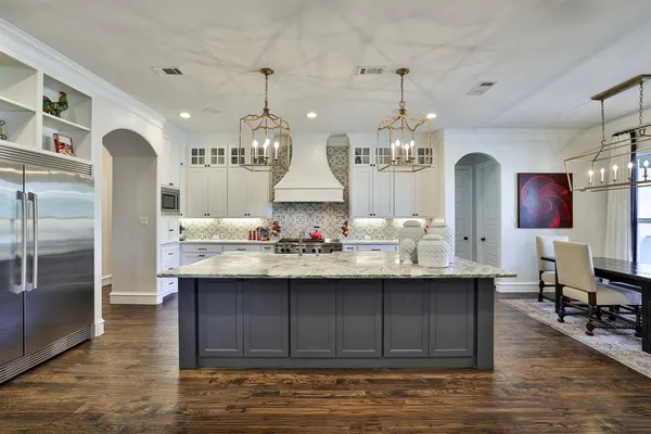 a kitchen with kitchen island granite countertop a sink cabinets and wooden floor