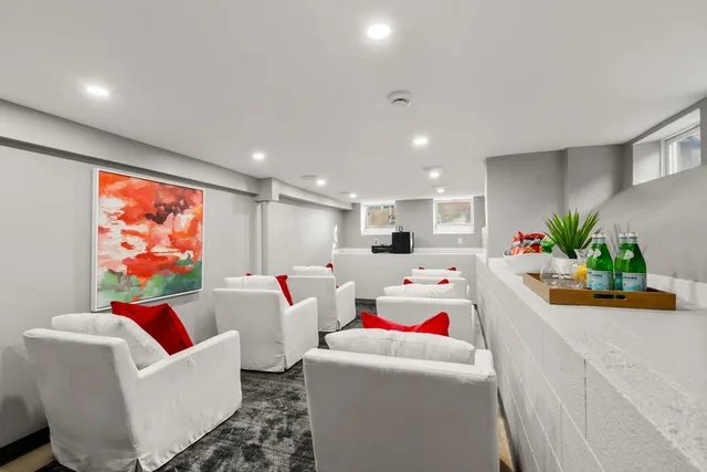 a living room with stainless steel appliances furniture a rug kitchen view and a chandelier