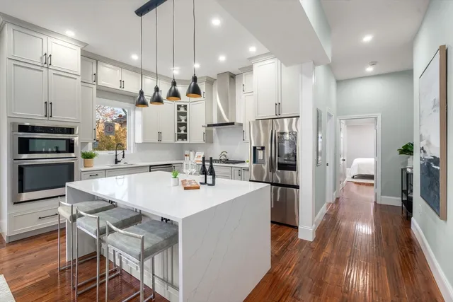a kitchen with a stove a sink and wooden floor