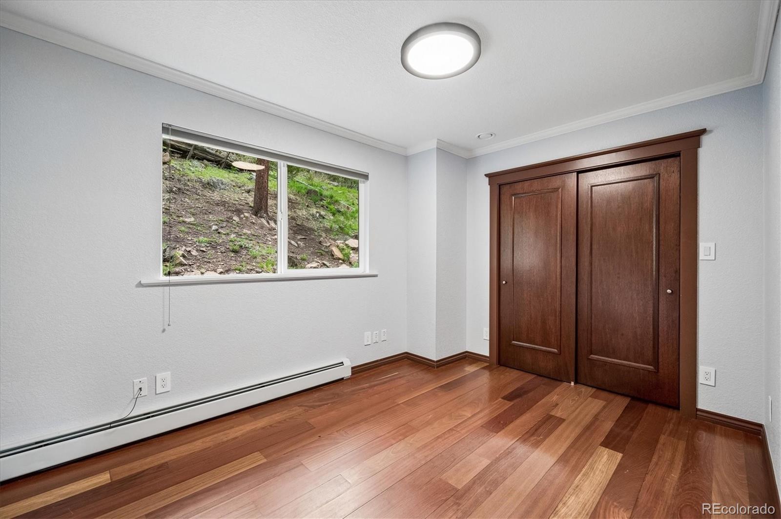 6747 South Brook Forest Road Evergreen, CO 80439 - Photo 26 of 49 an empty room with wooden floor closet and windows