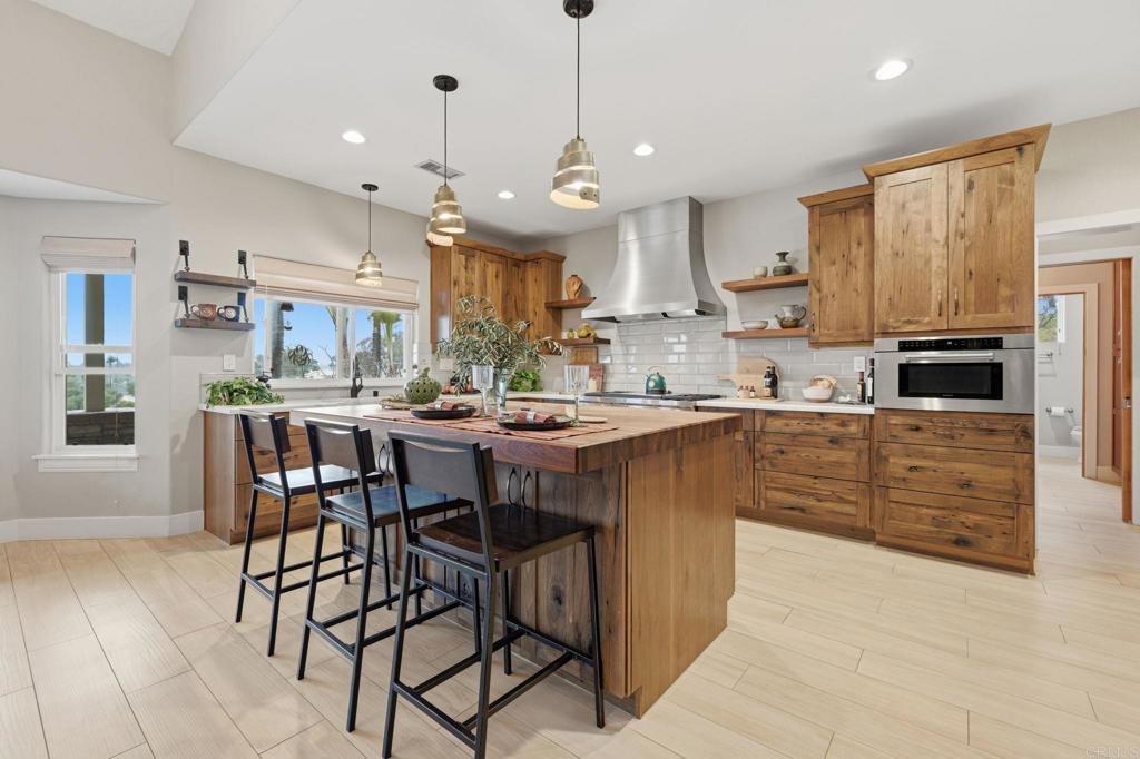 1655 Colina Vista Fallbrook, CA 92028 - Photo 12 of 63 a kitchen with stainless steel appliances kitchen island granite countertop a table chairs and a refrigerator