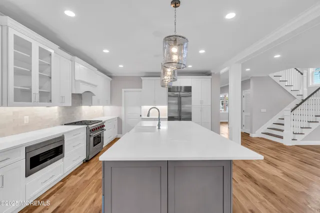 a kitchen with stainless steel appliances kitchen island granite countertop a sink a stove and a wooden floors