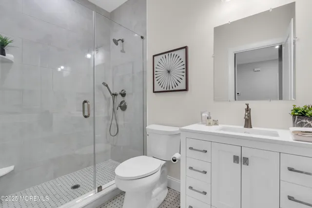 a bathroom with a shower sink vanity mirror and toilet