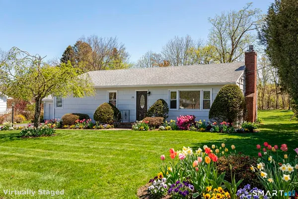 a front view of a house with garden and trees