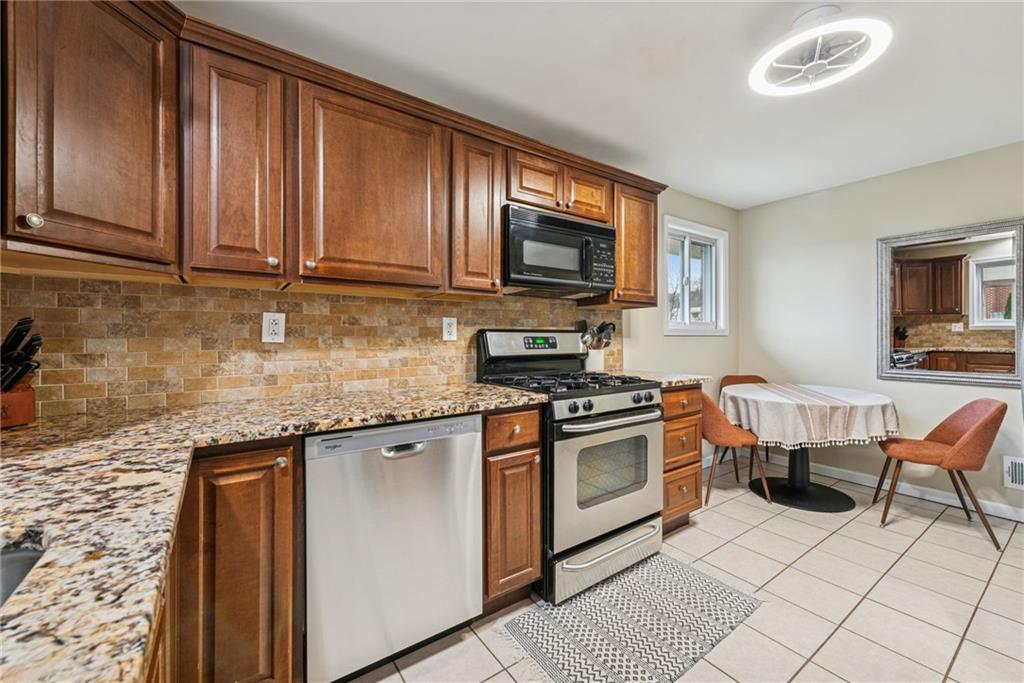 1000 Colfax Street Springdale, PA 15144 - Photo 6 of 25 a kitchen with stainless steel appliances granite countertop a stove top oven a sink dishwasher a dining table and chairs with wooden floor