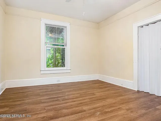 a view of an empty room with wooden floor and a window