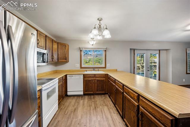 103 Saddlemountain Road Colorado Springs, CO 80919 - Photo 29 of 30 Kitchen with appliances with stainless steel finishes, a peninsula, light countertops, and light wood-style flooring