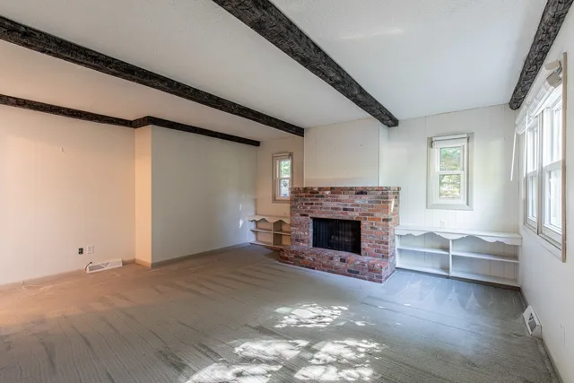 a view of a livingroom with a fireplace cabinet and windows