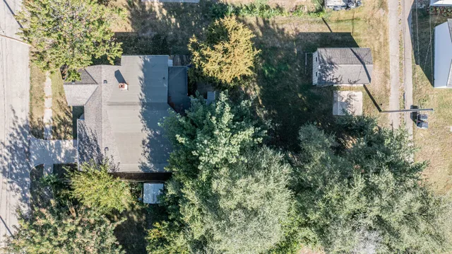 an aerial view of residential house with outdoor space and trees all around