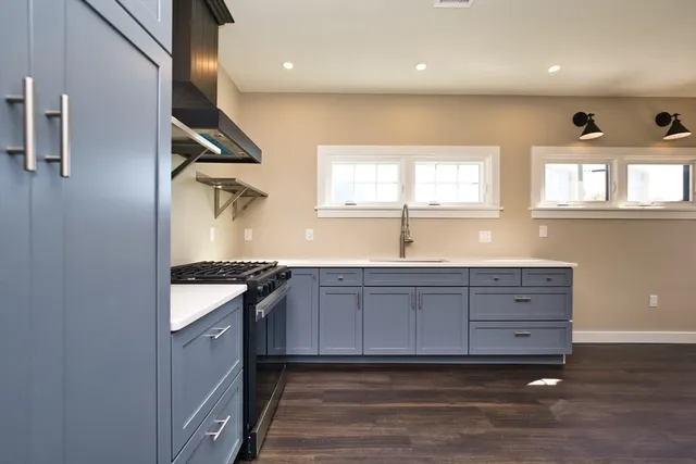 a kitchen with granite countertop a sink and a stove with wooden floor