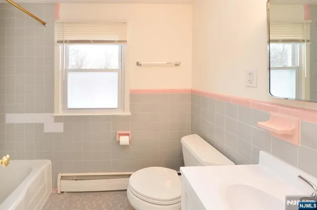 a white toilet and tub sitting next to a window