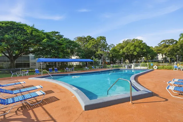 a view of a swimming pool with lawn chairs under an umbrella