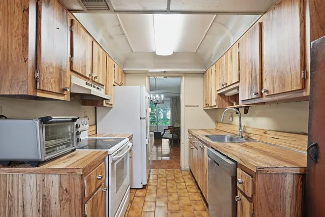 a kitchen with stainless steel appliances granite countertop a sink a stove and a wooden cabinets