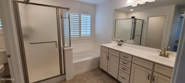 a spacious bathroom with a double vanity sink a mirror a shower and a bathtub