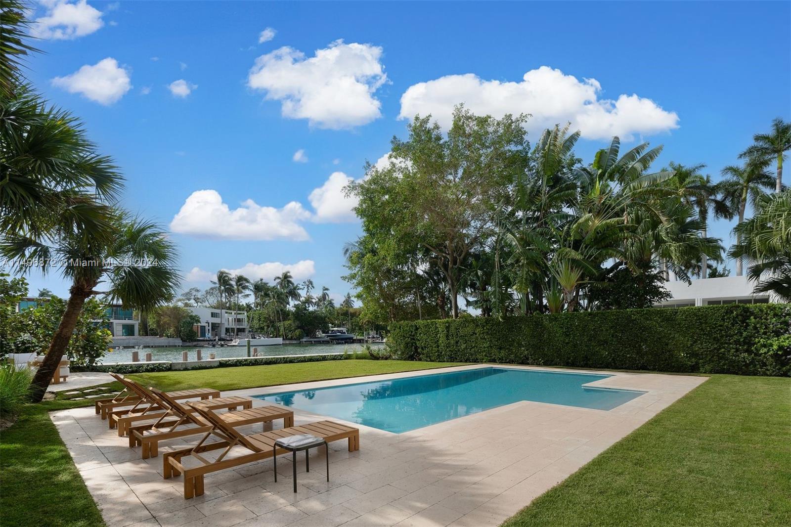 2770 Sunset Drive Miami Beach, FL 33140 - Photo 48 of 56 a view of a swimming pool with a lounge chair and trees in the background