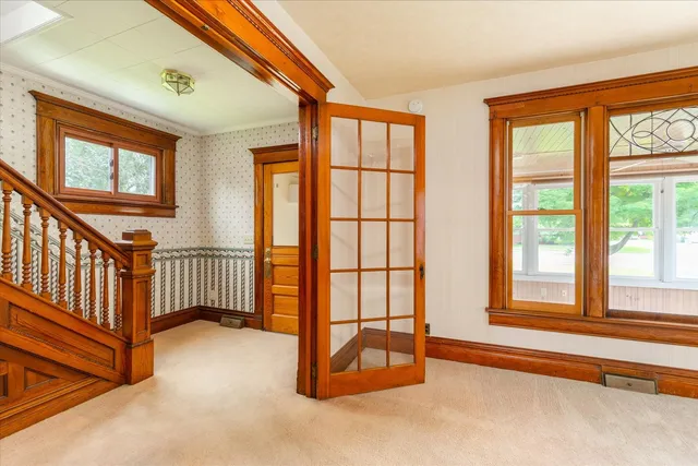 an empty room with chandelier fan and windows