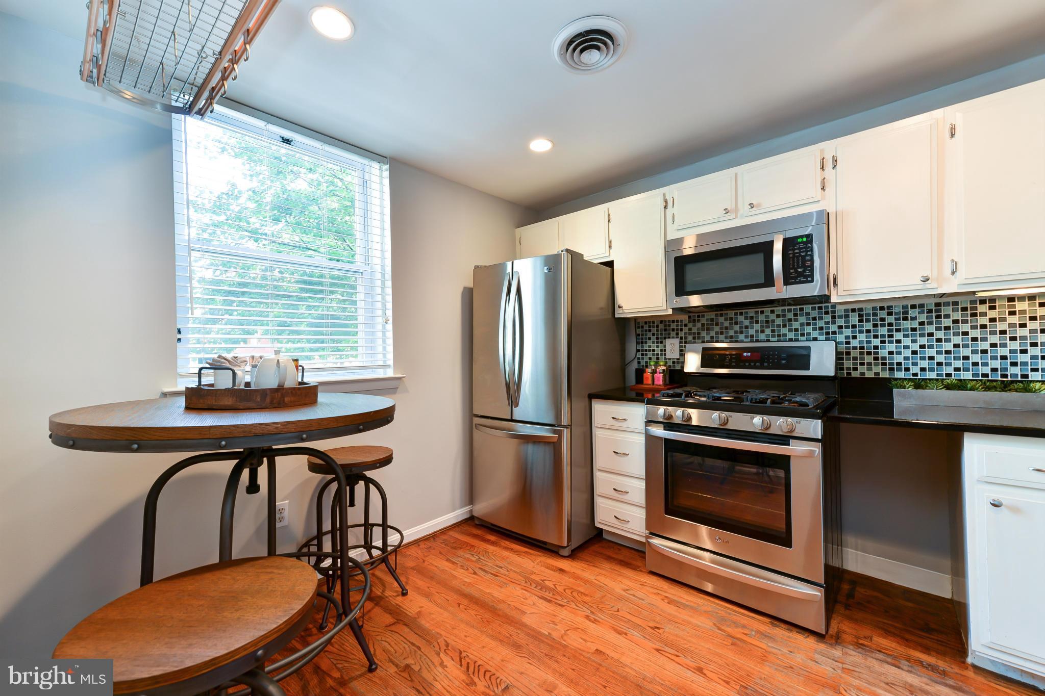 1243 Linden Place Northeast Washington, DC 20002 - Photo 9 of 30 a kitchen with stainless steel appliances a stove a sink a microwave a dining table and chairs