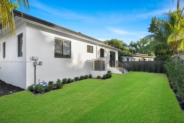 a view of a backyard with plants and large tree