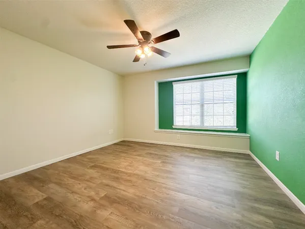 an empty room with window and ceiling fan