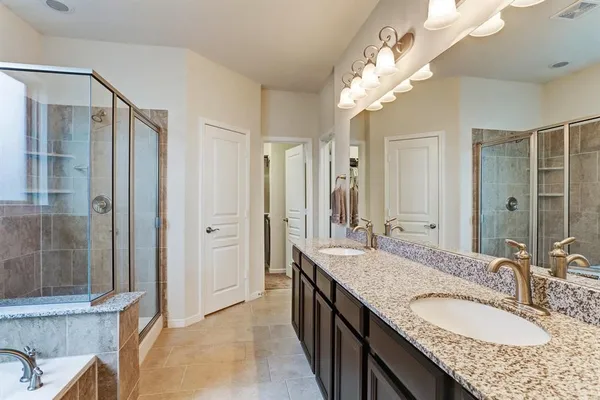 a bathroom with a granite countertop double vanity sink mirror and shower