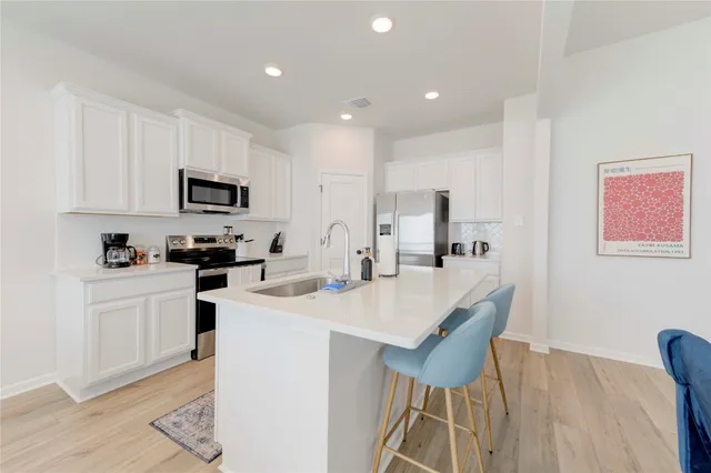 a kitchen with cabinets a sink a stove a dining table and chairs