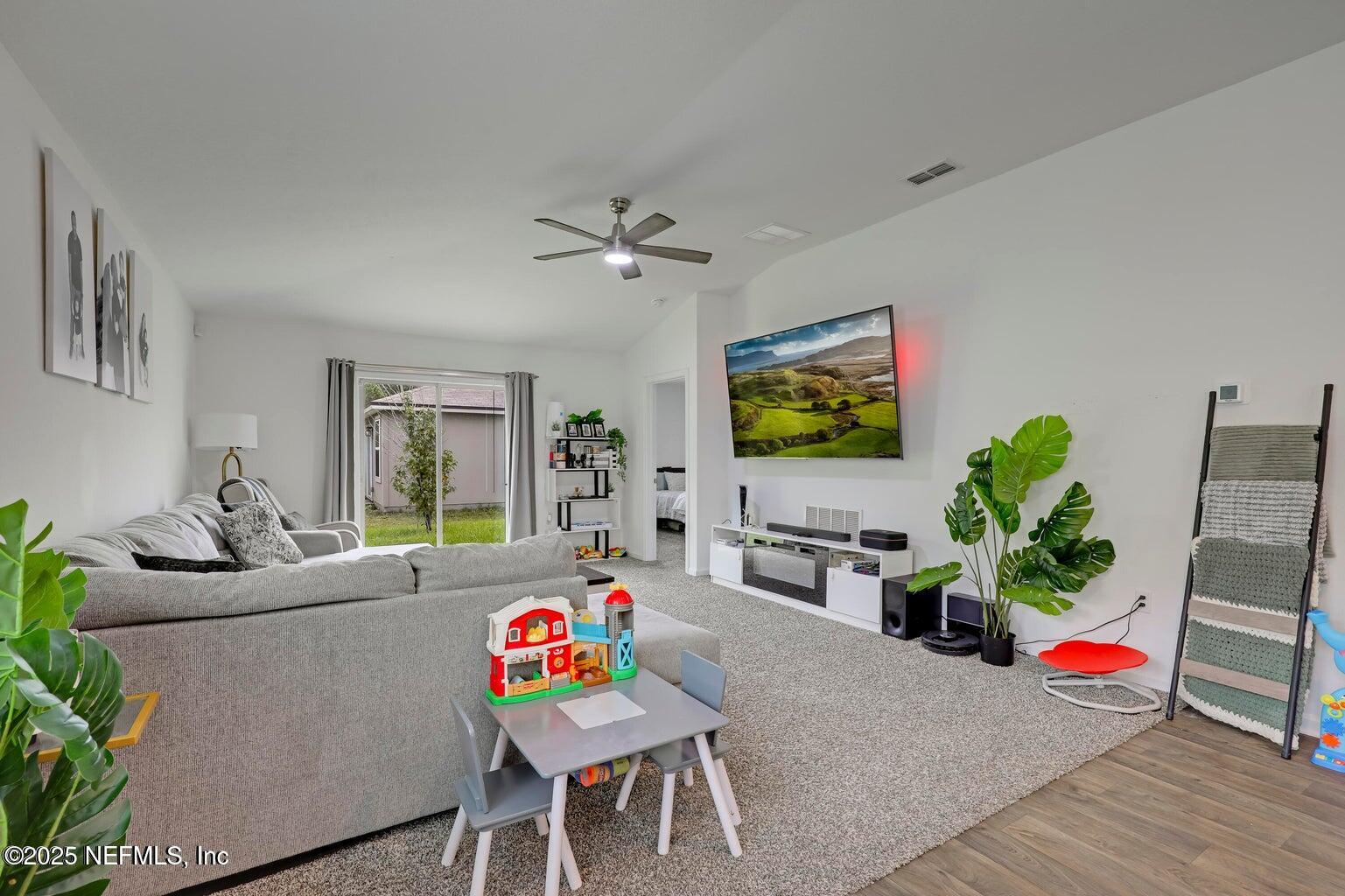 12633 Cacao Tree Trail Jacksonville, FL 32218 - Photo 23 of 44 a living room with furniture a chandelier and a flat screen tv