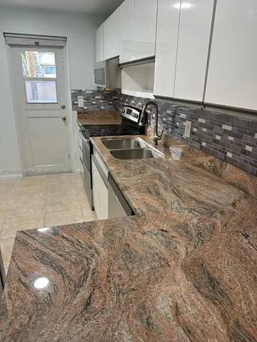 a kitchen with a sink a stove and cabinets