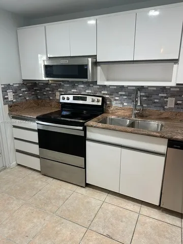 a kitchen with granite countertop a stove a sink and a microwave