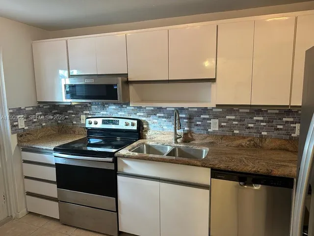 a kitchen with appliances a sink and cabinets