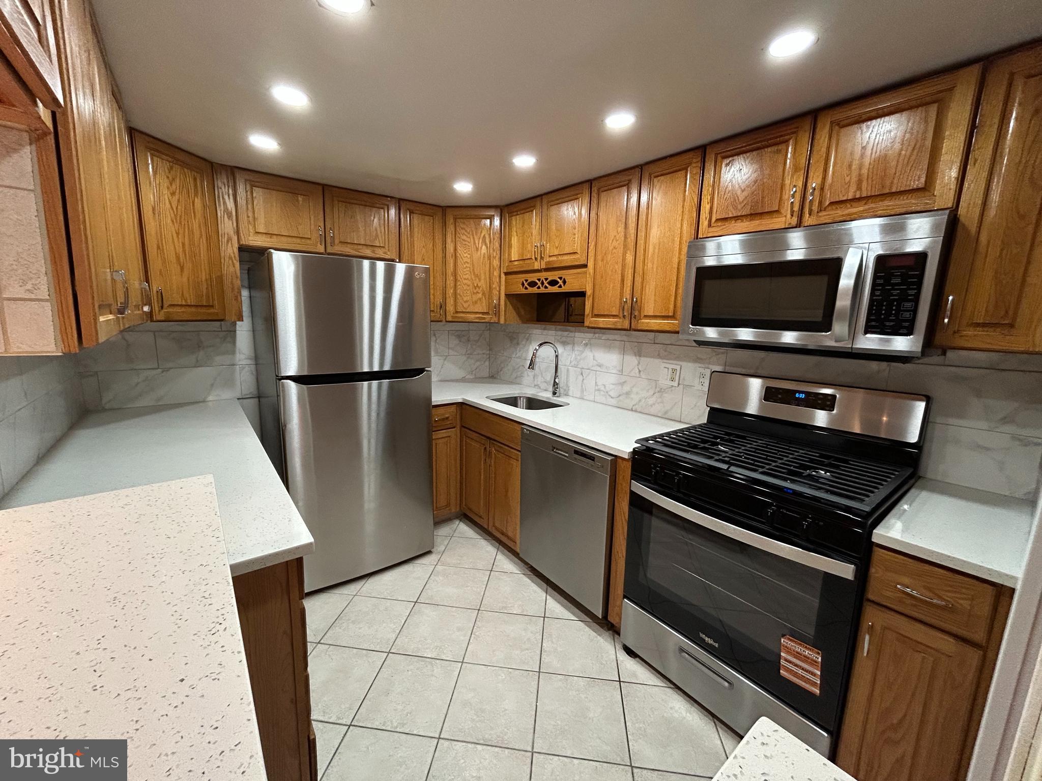 312 Old Forge Crossing, Unit 312 Devon, PA 19333 - Photo 10 of 21 a kitchen with a refrigerator a stove top oven a sink and cabinets