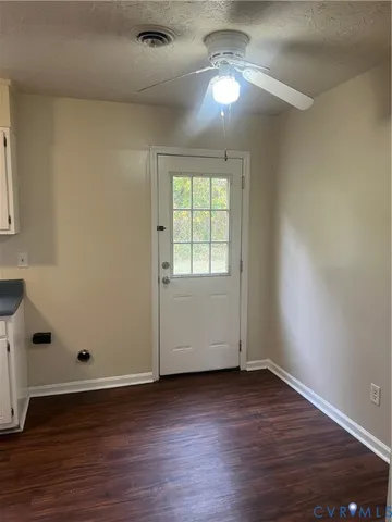 an empty room with wooden floor chandelier fan and windows