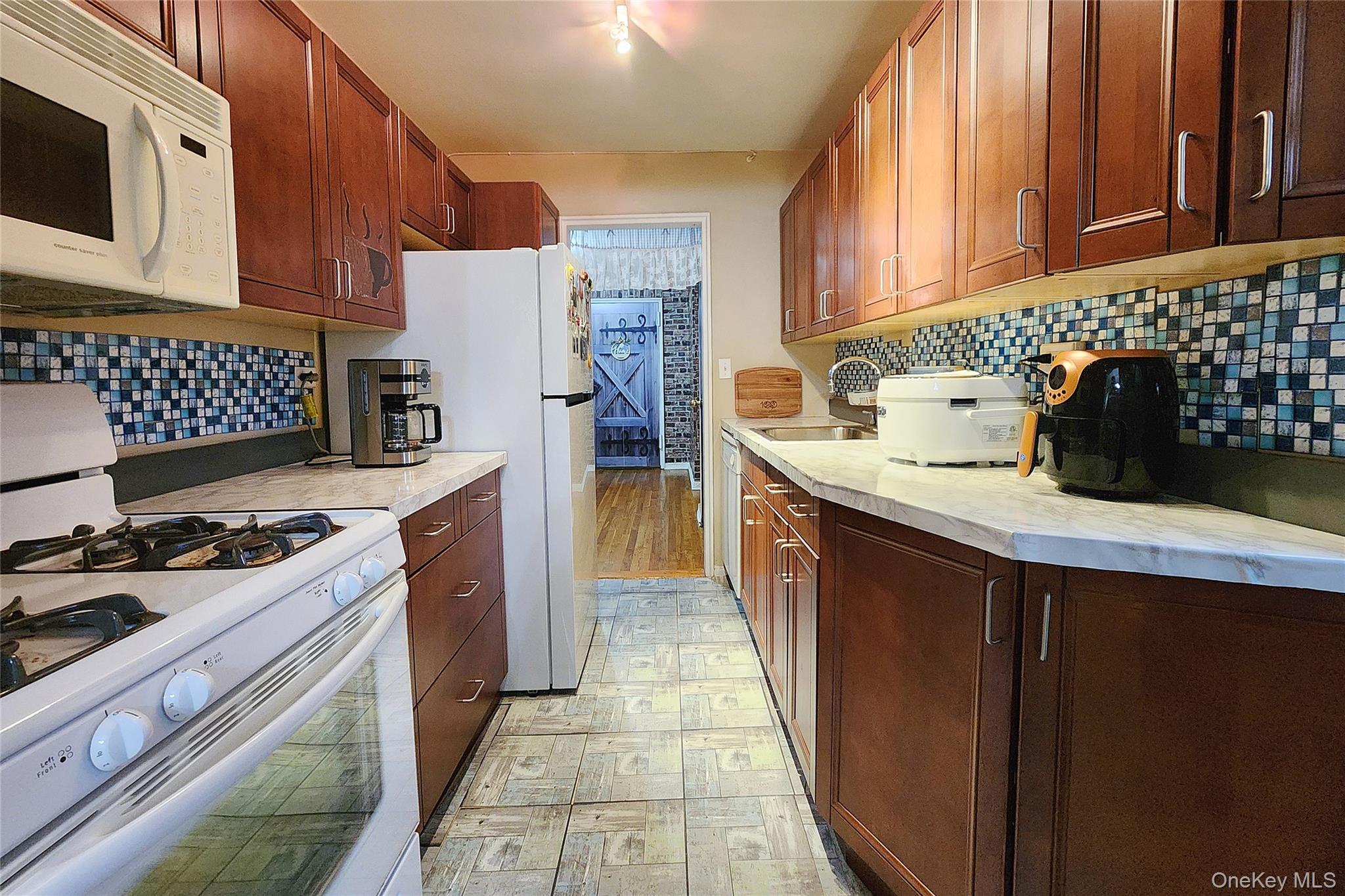 209-20 18th Avenue, Unit 5E Queens, NY 11360 - Photo 13 of 29 a kitchen with a sink a stove and refrigerator