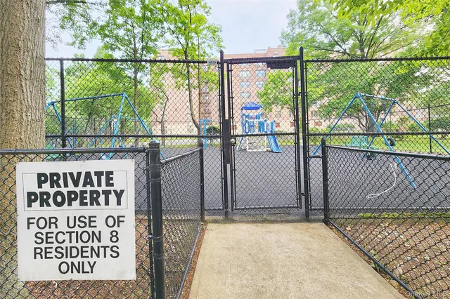 a front view of a building with garden and trees