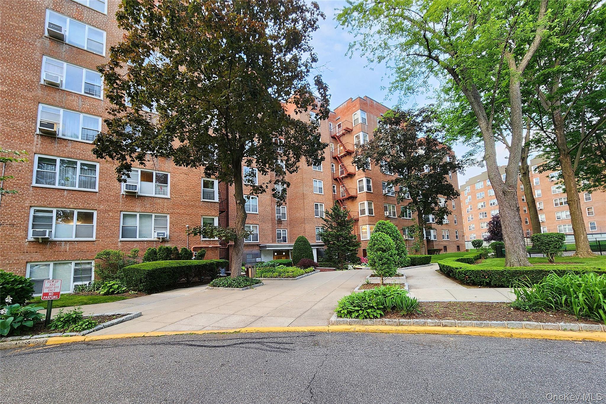 209-20 18th Avenue, Unit 5E Queens, NY 11360 - Photo 28 of 29 a front view of a building with garden and trees