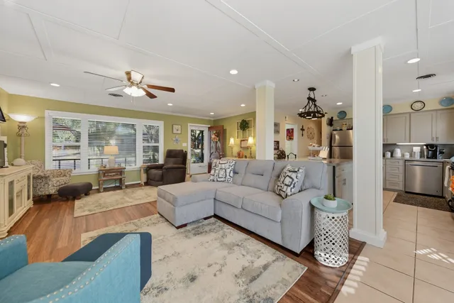 a living room with furniture kitchen view and a large window