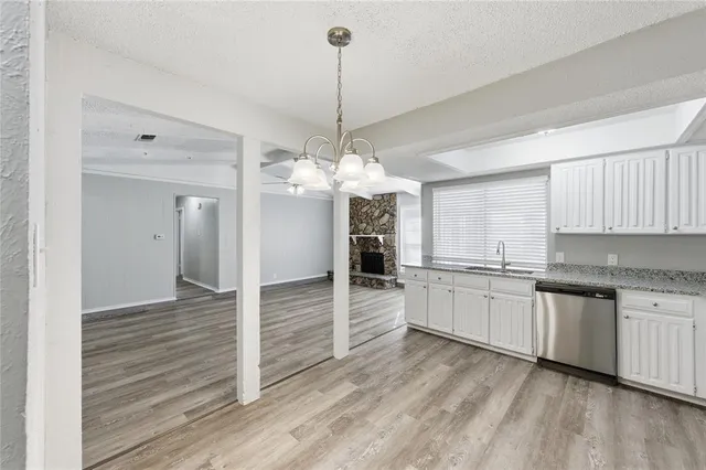 a kitchen with stainless steel appliances granite countertop a stove a sink and white cabinets with wooden floor