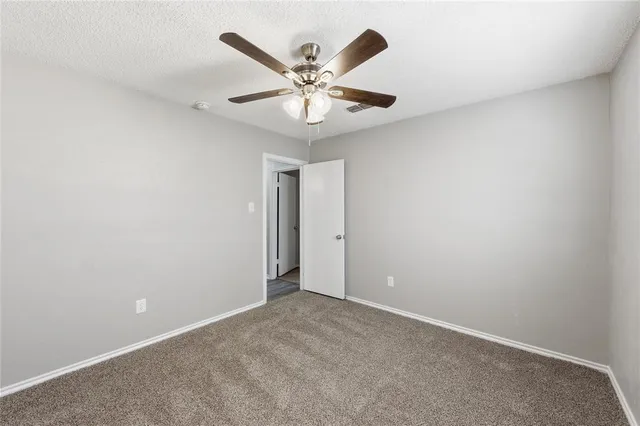 an empty room with closet and a ceiling fan